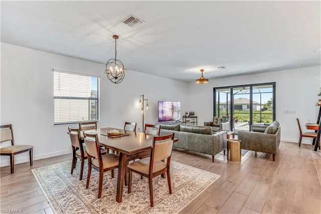 a dining room with furniture a chandelier and wooden floor