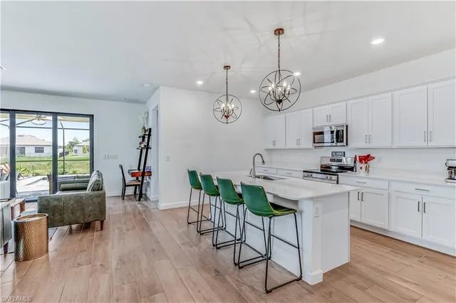 a kitchen with stainless steel appliances a dining table chairs stove and white cabinets