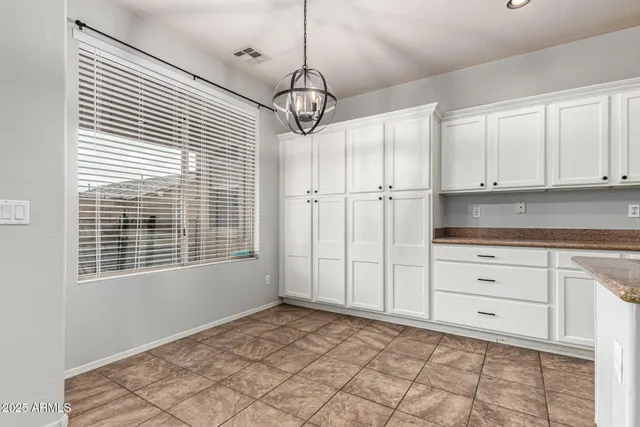 a kitchen with white cabinets and window