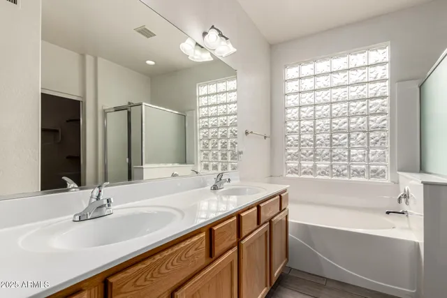 a bathroom with a bathtub double sink and a large mirror