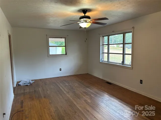 a view of an empty room with a window and wooden floor