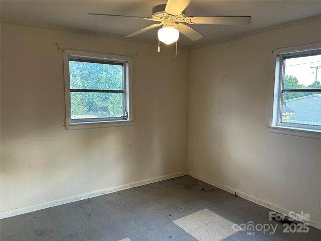 an empty room with windows and fan