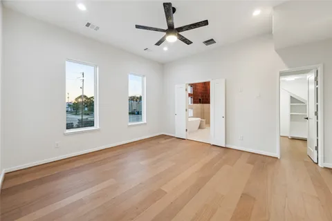a view of an empty room with a window and wooden floor