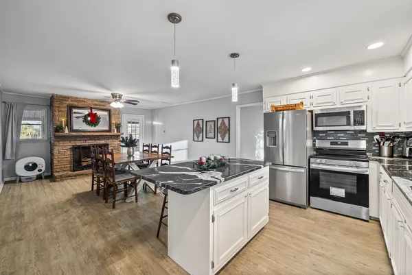 a kitchen with stainless steel appliances kitchen island granite countertop a sink cabinets and wooden floor