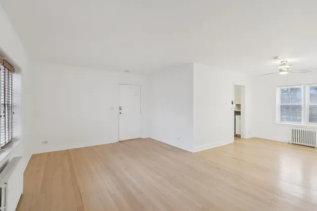 a view of empty room with wooden floor and fan