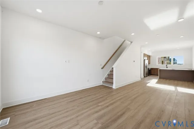 an empty room with wooden floor and stairs