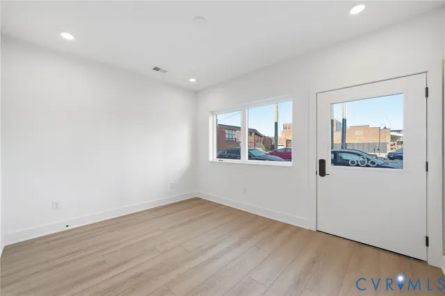 a view of an empty room with wooden floor and a window
