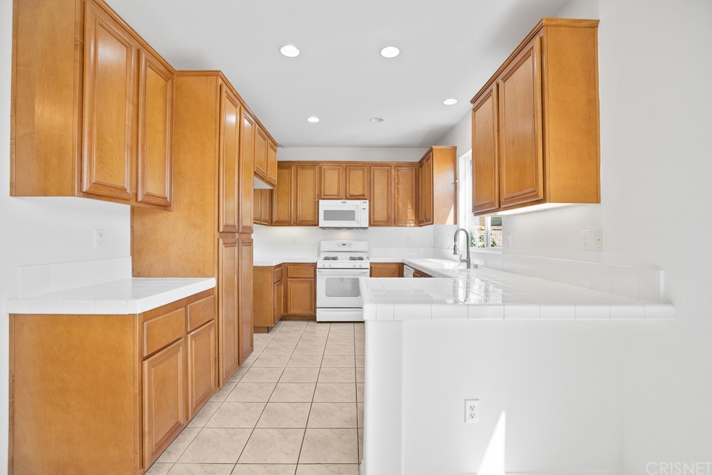 24063 Tango Drive Valencia, CA 91354 - Photo 13 of 46 a kitchen with stainless steel appliances granite countertop a sink a stove and a refrigerator