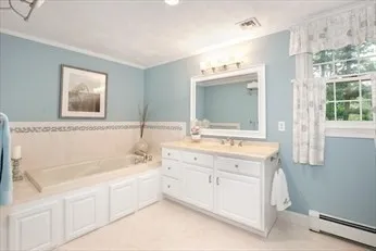 a spacious bathroom with a double vanity sink mirror and bathtub