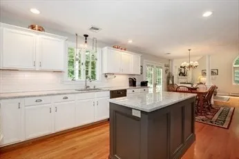 a kitchen with granite countertop sink stove and white cabinets with wooden floor