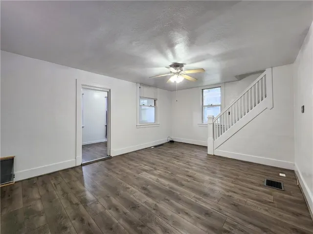 a view of an empty room with wooden floor and staircase