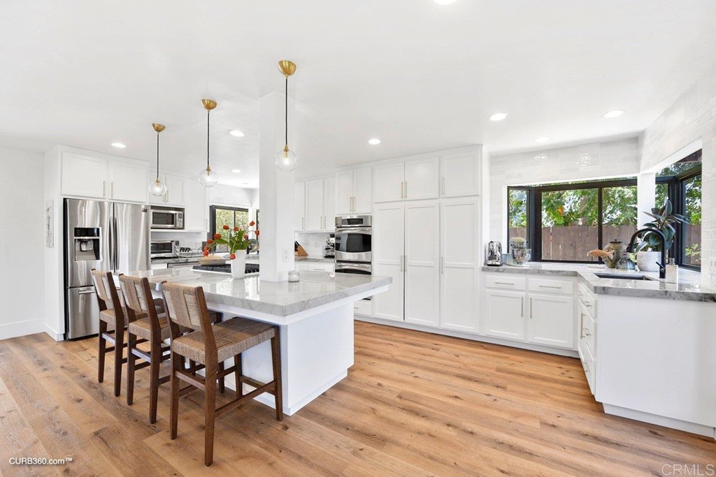 3815 Trieste Drive Carlsbad, CA 92010 - Photo 8 of 24 a kitchen with stainless steel appliances kitchen island granite countertop a table chairs and a sink