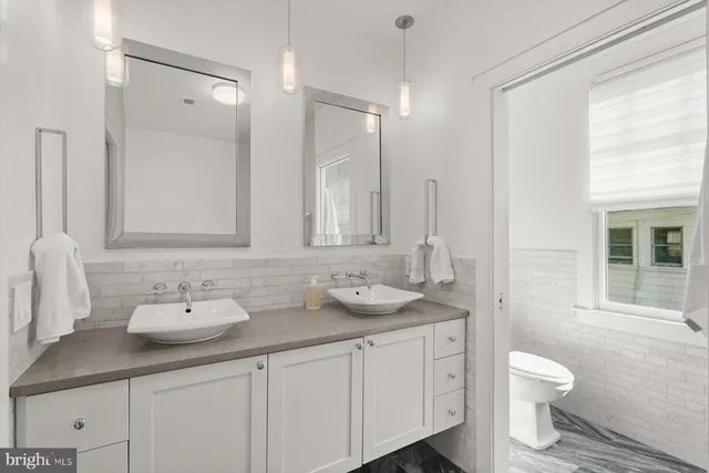 a bathroom with a granite countertop sink a toilet and a large mirror
