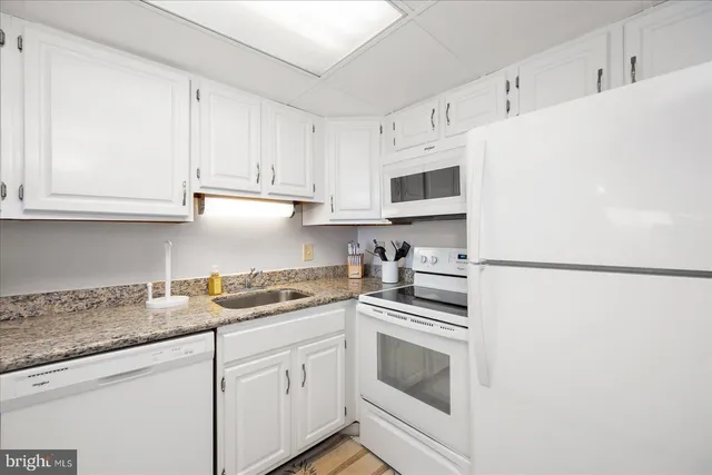 a kitchen with granite countertop white cabinets and white appliances