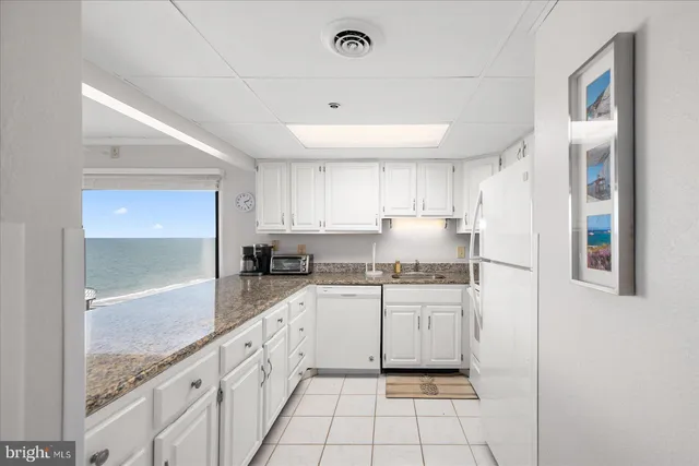 a kitchen with granite countertop white cabinets and white appliances