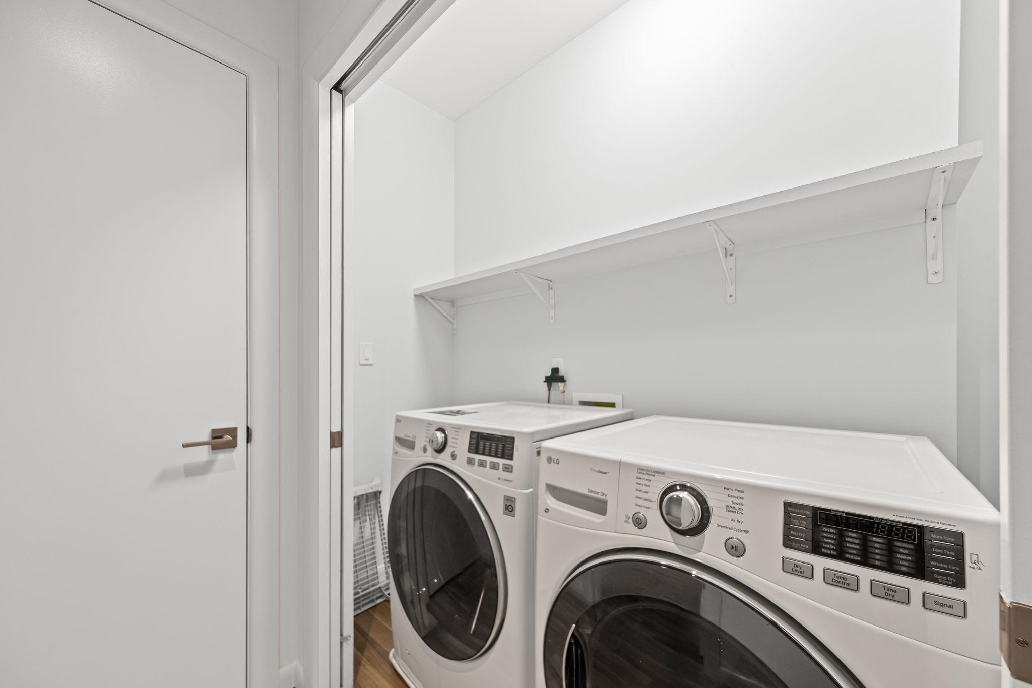 448 Tennessee Street Memphis, TN 38103 - Photo 19 of 39 Dedicated laundry area featuring a white front-load washer and dryer set, a full-width upper storage shelf, and light wood-finish flooring