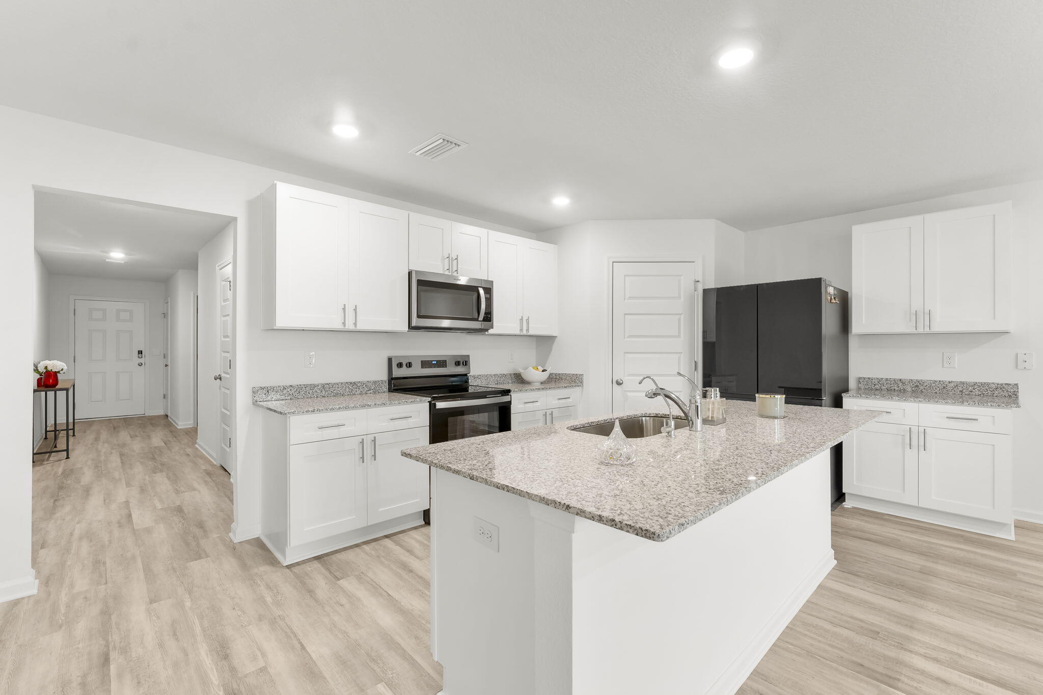 255 Riverwalk Circle Freeport, FL 32439 - Photo 8 of 40 a kitchen with stainless steel appliances granite countertop a sink stove refrigerator and white cabinets with wooden floor
