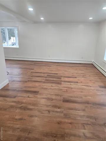 an empty room with a wooden floor and windows