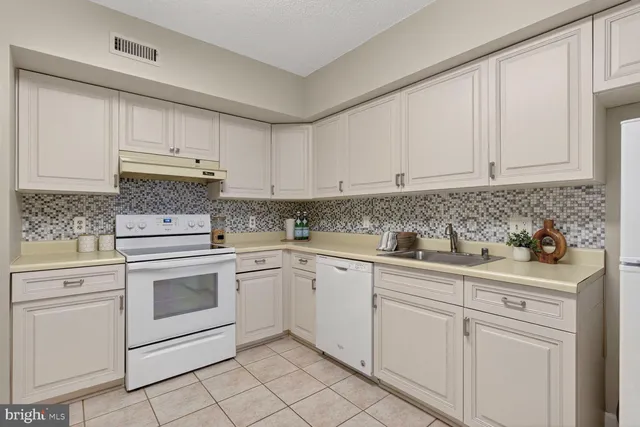 a kitchen with granite countertop white cabinets and white appliances