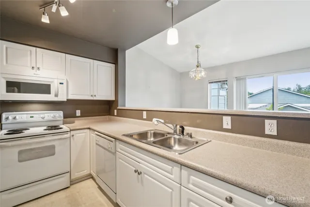 a kitchen with a sink dishwasher and white cabinets with wooden floor