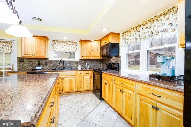 a large kitchen with kitchen island granite countertop a large window and a counter space