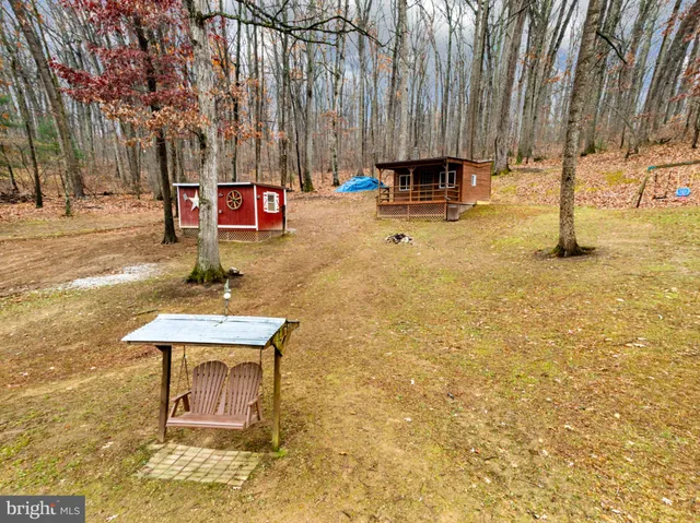 a backyard of a house with large trees and wooden fence