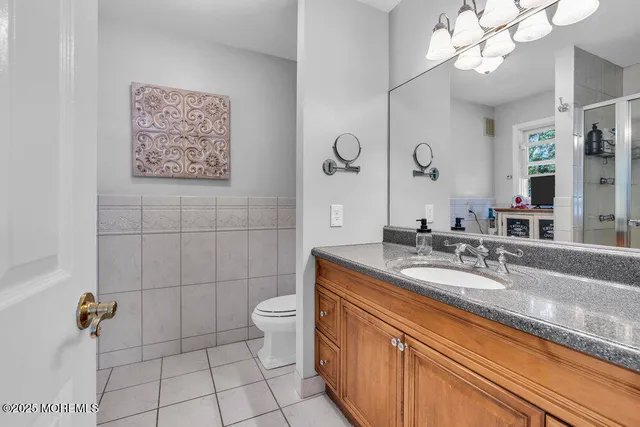 a bathroom with a granite countertop sink a toilet and mirror