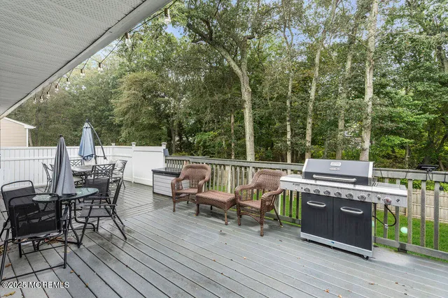 a view of a deck with table and chairs a barbeque with wooden floor and fence