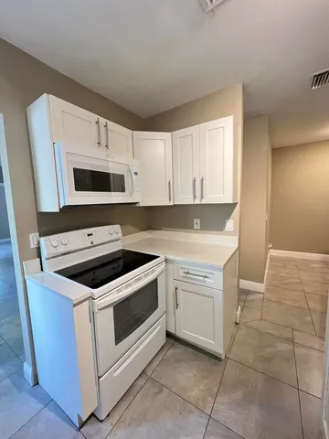 a kitchen with white cabinets and white appliances