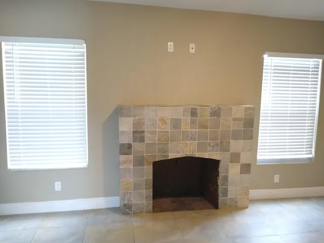 an empty room with a fireplace and windows