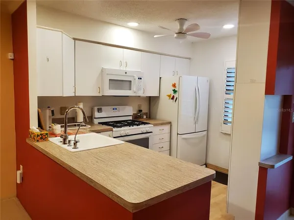 a kitchen with a refrigerator a sink and a stove top oven with wooden floor