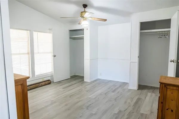 an empty room with wooden floor cabinet and windows