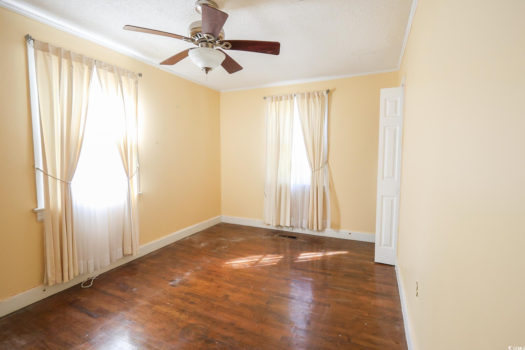 1841 Jasper Street Georgetown, SC 29440 - Photo 18 of 33 Empty room with a textured ceiling, dark wood-type flooring, ornamental molding, and ceiling fan