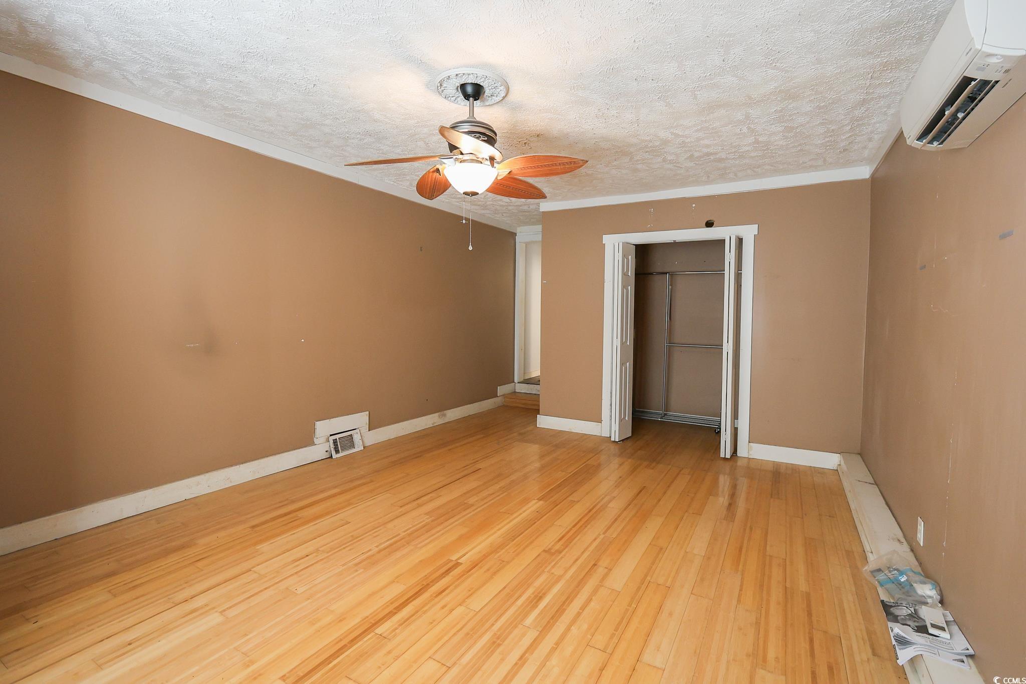 1841 Jasper Street Georgetown, SC 29440 - Photo 7 of 33 Unfurnished bedroom with light hardwood / wood-style flooring, ornamental molding, an AC wall unit, and a textured ceiling