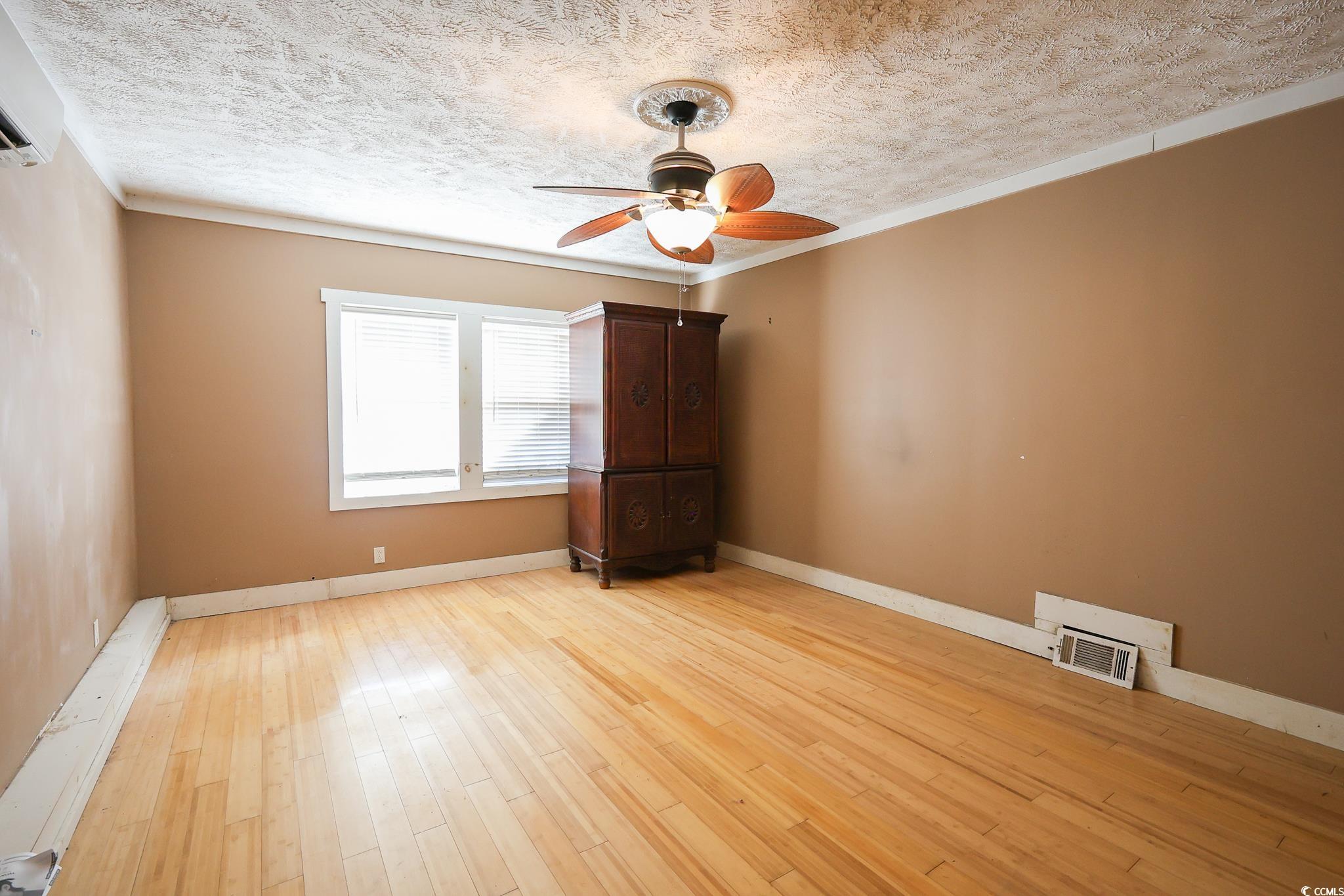 1841 Jasper Street Georgetown, SC 29440 - Photo 8 of 33 Empty room featuring ceiling fan, ornamental molding, a textured ceiling, and light hardwood / wood-style flooring