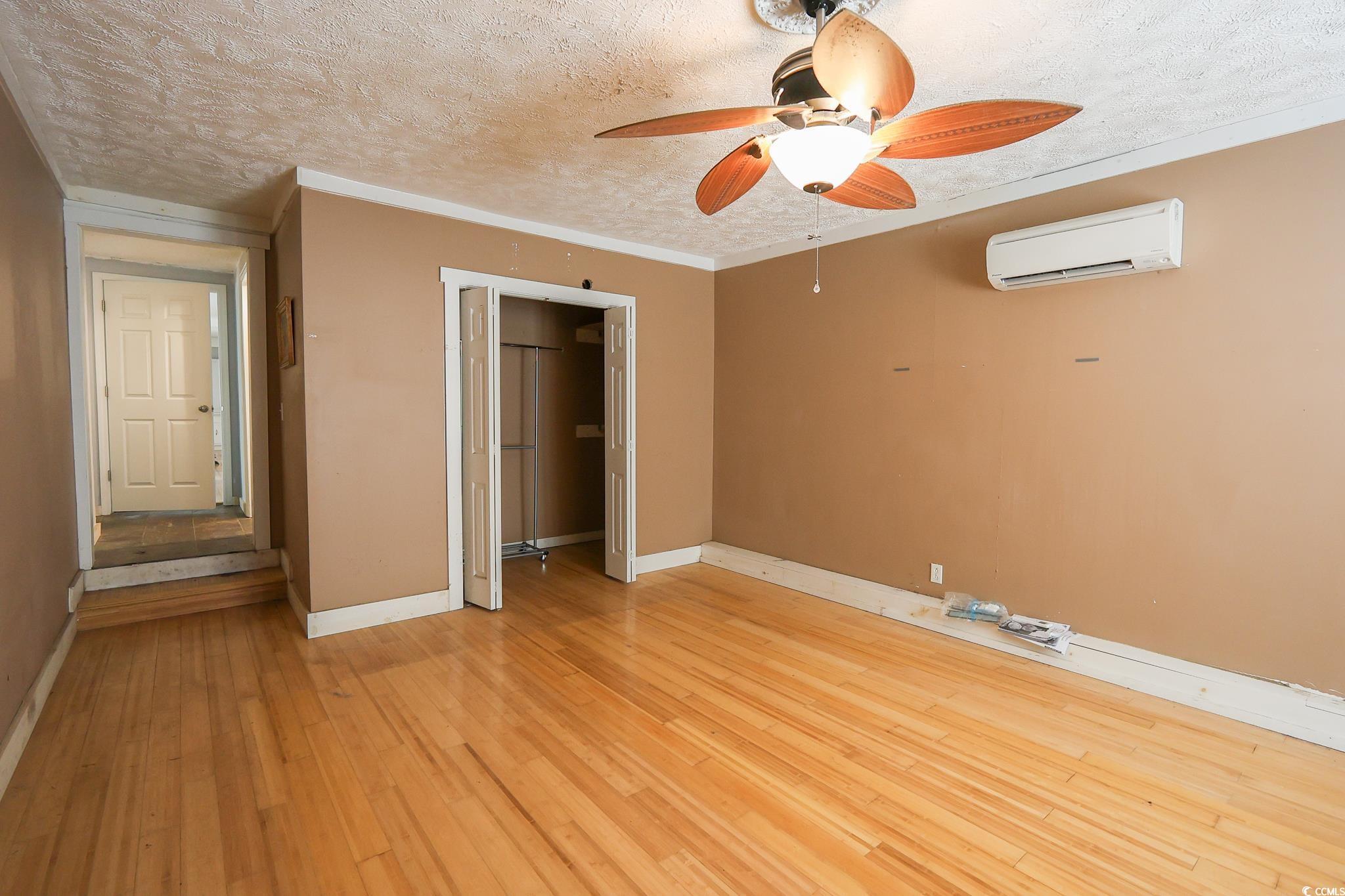 1841 Jasper Street Georgetown, SC 29440 - Photo 9 of 33 Unfurnished bedroom featuring a wall unit AC, light hardwood / wood-style floors, crown molding, a textured ceiling, and a closet