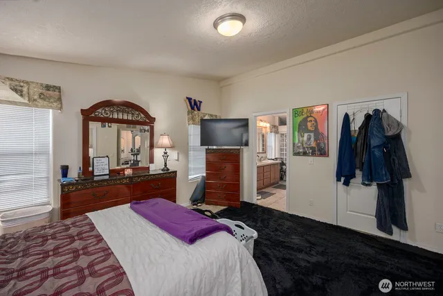a bedroom with a bed and a flat tv screen on dresser