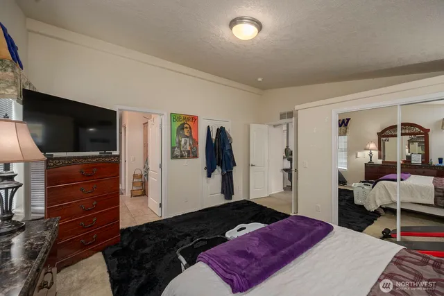 a bedroom with a bed and a flat tv screen on wall