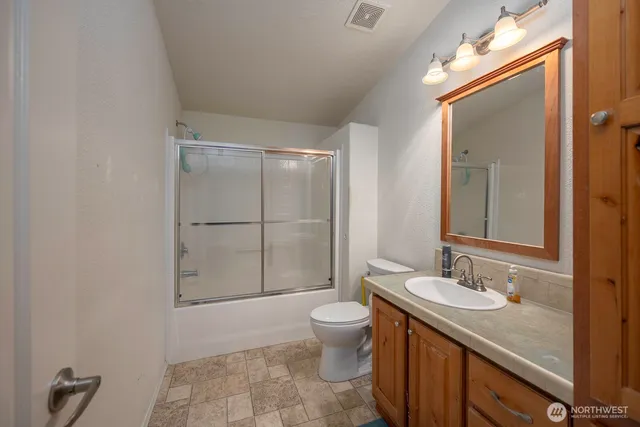 a bathroom with a granite countertop sink toilet and shower
