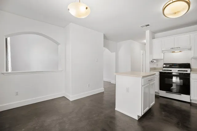 a kitchen with a white cabinets and wooden floor