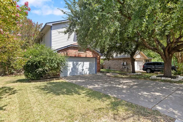 a view of a house with a yard and large tree