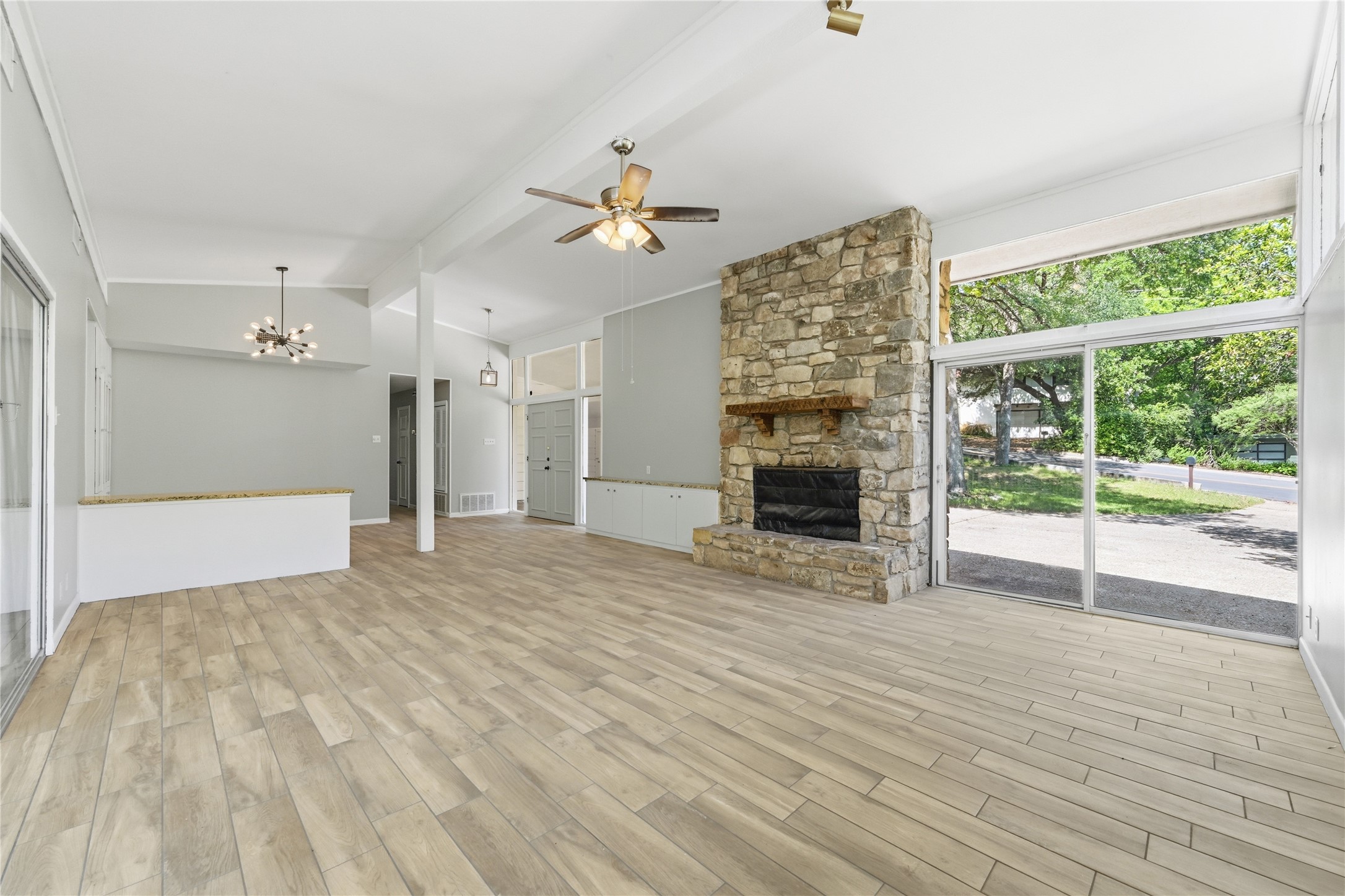 7 Hull Circle Austin, TX 78746 - Photo 6 of 17 A spacious living room with wood-look tile flooring and a grand stone fireplace.