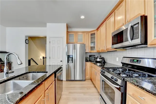a kitchen with stainless steel appliances granite countertop a sink stove and refrigerator