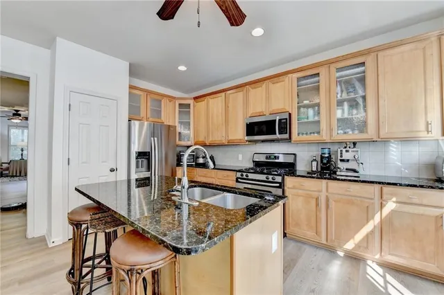 a kitchen with stainless steel appliances granite countertop a stove top oven a sink a dining table and chairs with wooden floor