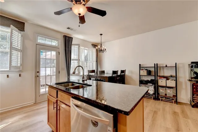 a kitchen with stainless steel appliances granite countertop a sink dishwasher and a refrigerator with wooden floor