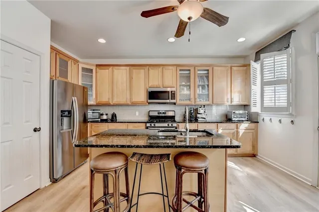 a kitchen with stainless steel appliances granite countertop a stove a sink dishwasher a refrigerator and a microwave oven with wooden floor