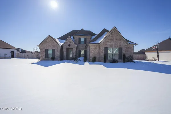 a front view of a house with a yard covered in snow