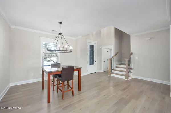 a dining room with wooden floor a chandelier a wooden table and chairs