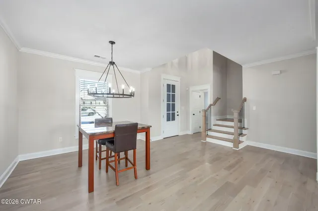 a dining room with wooden floor a chandelier a wooden table and chairs