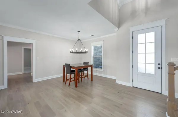 an empty room with wooden floor chandelier and windows